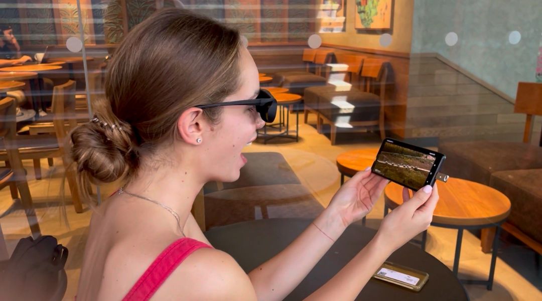 A woman enjoys a 3D movie on her phone using Rekindle 3D Glasses, black DLP-link rechargeable active shutter glasses, paired with the Rekindle 3D Stick USB Type-C connector for an immersive 3D viewing experience on the go.